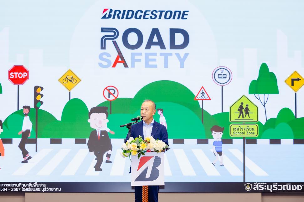 A person standing at a podium with a podium and a sign on the wall Description automatically generated